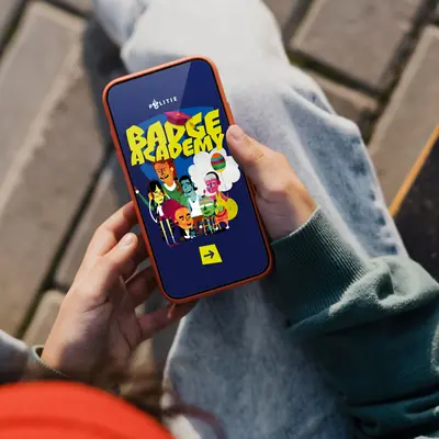 A person’s hands holding a smartphone in a red case, displaying the Badge Academy app splash screen with the Dutch Police logo, bold yellow title, and illustrated cast of characters.