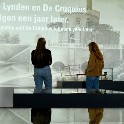Two visitors standing in front of a large projected historical illustration of the Cruquius pumping station, part of the museum’s narrative on land reclamation.