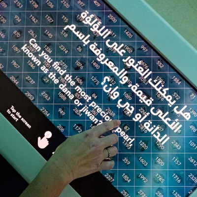 Close-up of a touchscreen game interface with a grid of numbered pearl illustrations, inviting visitors to find the most precious pearl known as the Dana or Jiwan.