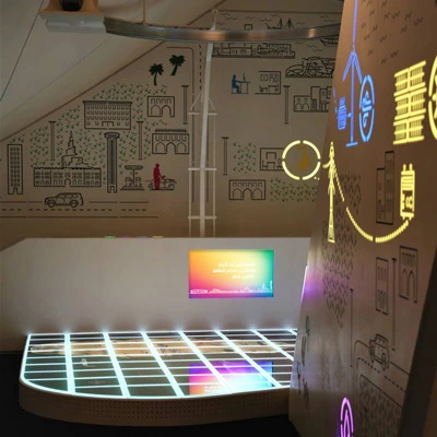 Wide view of an immersive energy-themed room with glowing floor tiles and colorful wall graphics depicting Qatar’s energy landscape and infrastructure.