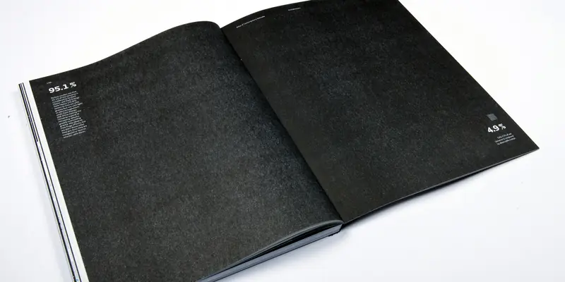 High-angle shot of an open book with a minimalist black two-page spread. The left page features text under a “95.1%” heading explaining dark matter, while the right page is mostly blank, featuring only a small “4.9%” statistic about observable matter in the bottom corner.