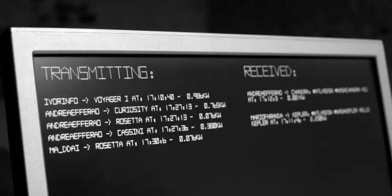 Close-up of a computer monitor displaying retro, pixelated white text on a black screen. The screen is divided into a “TRANSMITTING:” column showing outbound messages to deep space probes, and a “RECEIVED:” column showing inbound confirmations.