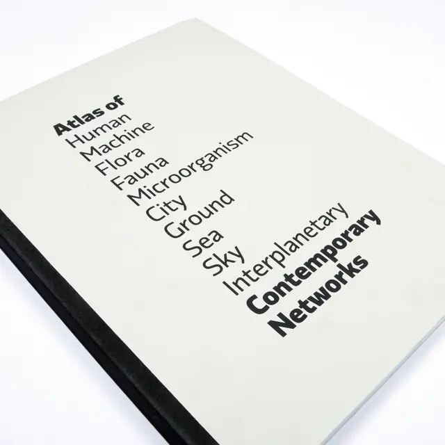 Angled shot of a book cover with an off-white background. Black text lists words like “Human,” “Machine,” “Flora,” “Fauna,” and “Interplanetary” in a descending stepped pattern, ending with the bold title “Contemporary Networks.”