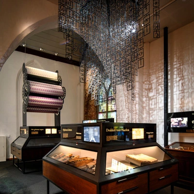 Typography-themed station with metal type installations hanging overhead, display cases with printing materials below, and stained glass windows adding depth to the gallery.