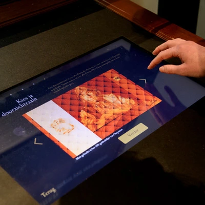 Detailed view of a digital display featuring an interactive design tool, where a user is selecting security features for a banknote as part of an educational museum experience.