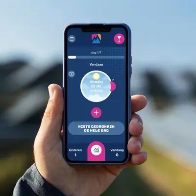 The main app dashboard on day 1 of 7, displaying the text “Vandaag” above a central pink plus icon and a large blue button that reads “NIETS GEDRONKEN DE HELE DAG” to quickly log a sober day.