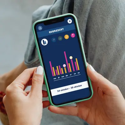 A hand holding a smartphone displaying the “OVERZICHT” dashboard screen. The interface shows a weekly bar chart comparing alcohol (pink bars) and cigarette (orange bars) usage data from October 24 to October 30.