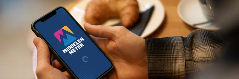 Close-up of a smartphone screen displaying the dark blue splash screen of the “Middelen Meter” app, featuring a geometric mountain logo in pink, yellow, and blue with a loading spinner.