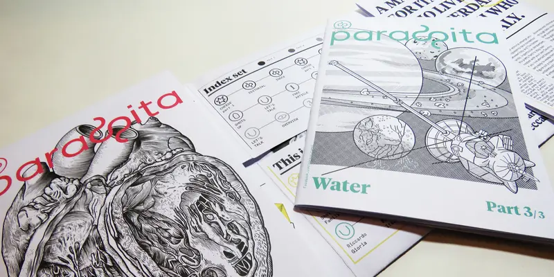 Several opened and closed issues of “Parasita” magazine scattered on a surface. Visible pages show an “Index set” roadmap diagram, a planetary space cover labeled “Water Part 3/3”, and the human heart illustration issue.