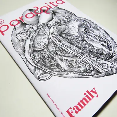 A close-up, angled view of the cover of “Parasita” magazine, subtitled “Family”. It features a detailed black and white cross-section illustration of a human heart, with the title text printed in vibrant pink.